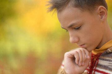 Close up portrait of boy in autumn park praying
