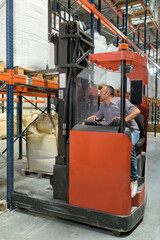 warehouse worker using fork truck to load pallet on racking - obrazy, fototapety, plakaty