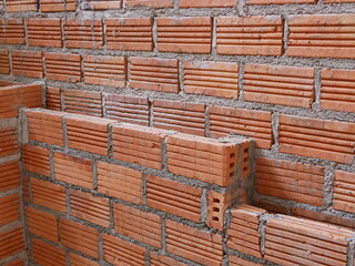 Classic red bricks laid to make two-layer wall waiting to be plastered by cement