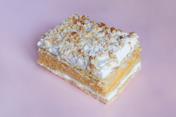 Millefeuille made with puff pastry and filled with pastry cream and meringue. The dessert is topped with toasted chopped almonds and icing sugar on colorful texture background. Traditional sweet.