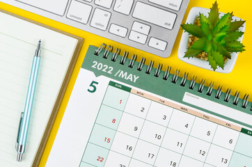 May 2022 desk calendar and diary with keyboard computer.