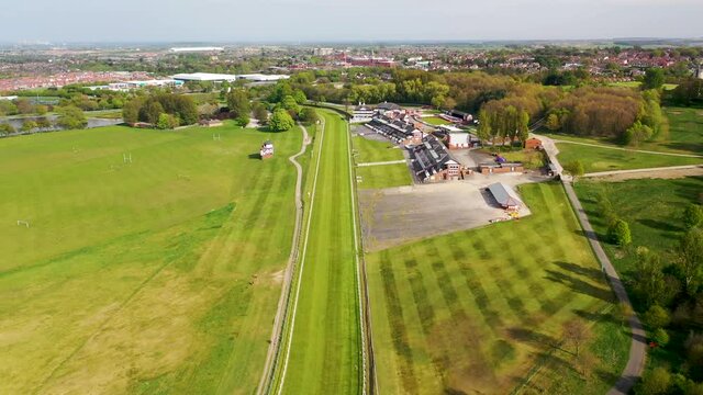 Aerial footage of the Pontefract race course located in the town of Pontefract in West Yorkshire in the UK, showing the main building and horse racing course, with the town of Castleford in the back
