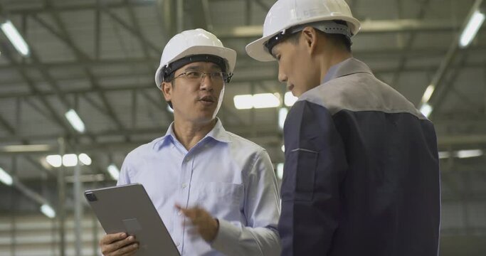 Two engineer talking together at factory. They discuss about project plan at factory.