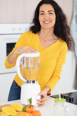beautiful adult woman making healthy juice at kitchen