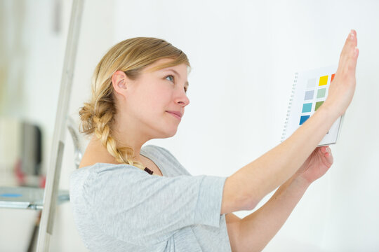 woman selecting home interior paint color from swatch catalog