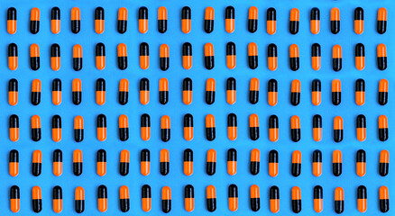 Black and yellow pills on a blue background. Lots of pills. Homeopathy medicine alternative herbs, health care concept and pills. Flatlay. View from above.