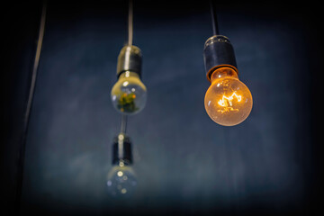 Glass dusty light bulb in a vintage base hanging on an electrical wire