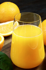 Fresh orange juice in a glass on a wooden background. Fresh Orange fruits with green leaves. Healthy vegan food. Vitamins food.Ripe oranges.Flat lay. Vertical orientation.