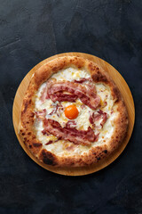 Pizza Carbonara on black stone background. Italian Pizza Carbonara with Bacon, Egg and Cheese, copy space.