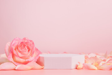 Empty podium with pink rose flowers on pink background to display products, gift or cosmetics....