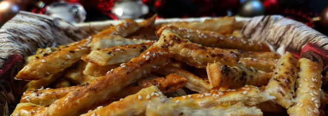 View of puff pastry salty sticks sprinkled with cumin and sesame seeds in a wicker basket, with...