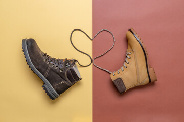 Two yellow and brown men's and women's winter suede leather stylish boots on color background. Laces in heart shape. Casual trendy footwear, shopping, sale, shoes fashion concept. Flat lay, top view