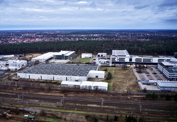 Obraz premium Aerial view from the southern edge of the city of Gifhorn, Germany, showing a development of single-family homes behind a new industrial park with large commercial buildings in the foreground