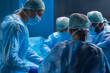 Multiracial team of professional medical surgeons performs the surgical operation in a modern...