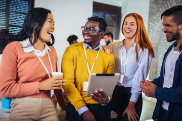 Happy business colleagues using digital tablet while standing in a office