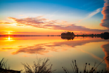 Gorgeous panorama on the lake at sunset with the reflection of the clouds on the water, vivid colors