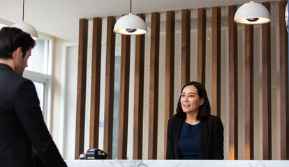 Friendly receptionist woman working at desk in hotel lobby. Leisure and travel at holidays.