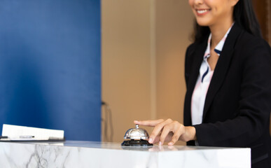 Ring bell call service with hand on hotel reception desk