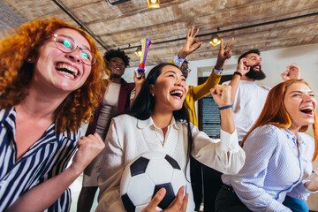 Happy casual business people or football fans watching soccer on tv and celebrating victory. Friendship, sports and entertainment concept.