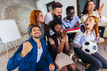 Happy casual business people or football fans watching soccer on tv and celebrating victory. Friendship, sports and entertainment concept.