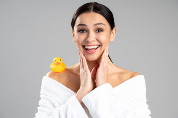 Obraz na płótnie Canvas Wow. Amazed brunette woman looking at the camera with surprised emotions while posing with cute rubber duck at her shoulder