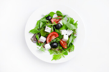 Fresh Greek salad in white plate isolated on white. Space for text. top view