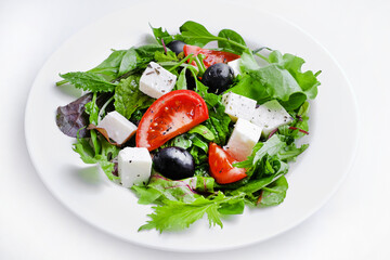 Fresh Greek salad in white plate isolated on white. Space for text. top view