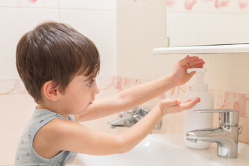 The boy soaps his hands with hand-washing foam. Cleanliness and hygiene.