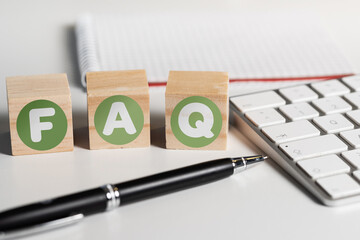 FAQ on wooden blocks on office desk with computer keyboard, frequently asked questions concept