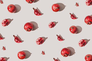 Creative pattern made of fresh pomegranates on pastel grey background with sunlit. Minimal style....