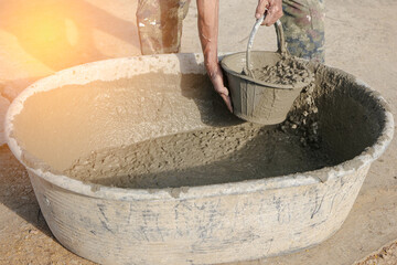 Construction worker use a bucket to scoop the ready-mixed cement with your bare hands in...