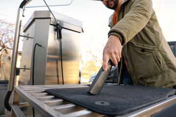 Man cleaning auto carpets with vacuum cleaner at self-service car wash, closeup