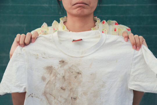 Girl Showing Dirty Stain On Kid Shirt With Bad Feeling From Playing Hard On Mud Stain. Dirty Stain For Cleaning Concept Work.