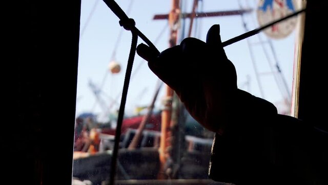Fisherman Pulling the Rope of the Ship Horn inside the Wheelhouse of an Old Fishing Boat in Mar del plata, Argentina. Close-Up.  
