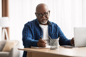 African American Man Taking Notes Sitting At Laptop In Office - obrazy, fototapety, plakaty