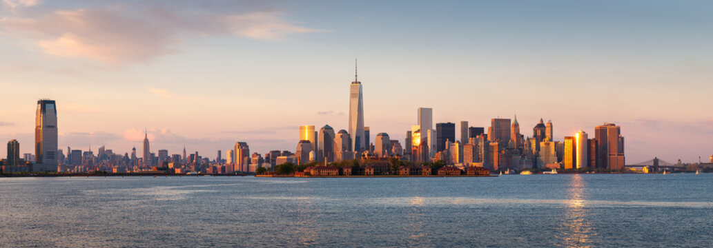 New York City Lower Manhattan skycrapers panoramic view at sunset. Ellis Island in New York Harbor with the World Trade Center