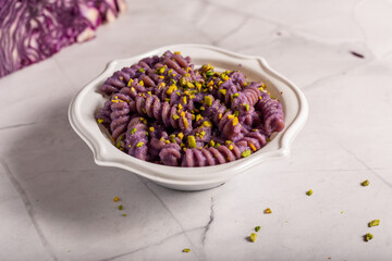 Fusilli pasta with purple cabbage cream and chopped pistachios. Dish suitable for a vegan diet.