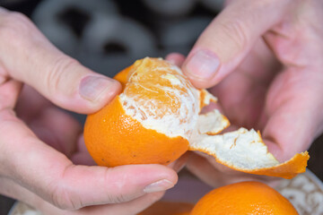Woman peels yellow tangerine. Eats fruits and vitamins.