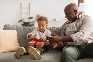 African American Grandpa Giving Wrapped Gift To Grandson At Home