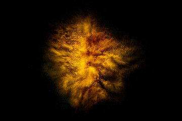 Explosion of yellow, golden color, fluid and neoned powder on dark studio background with copy space