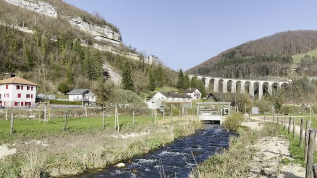 View of the Saint-Ursanne viaduct with the Doubs river flowing in the park