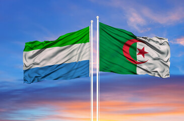 Algeria and Sierra Leone two flags on flagpoles and blue cloudy sky