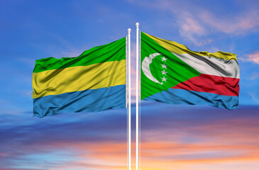 Gabon and Comoros two flags on flagpoles and blue cloudy sky