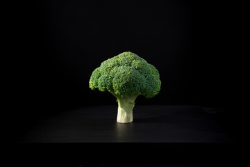 Un cogollo crudo de brócoli fresco. Fondo de árbol verde aislado sobre fondo negro