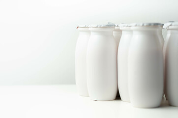 White plastic yogurt bottles on white background, typical packaging for dairy products
