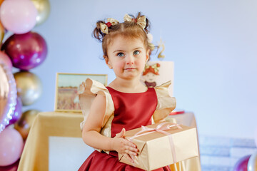Closeup of cute two years old baby girl celebrating her birthday in front of her tasty cake