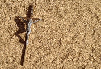 Christian crucifix on sand in bright sunlight
