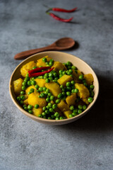 Indian food item alu matar or peas and potato masala in a bowl.