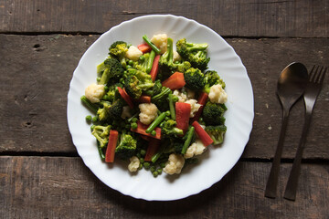 Fresh boiled vegetables tossed and served in a white plate. Top view.