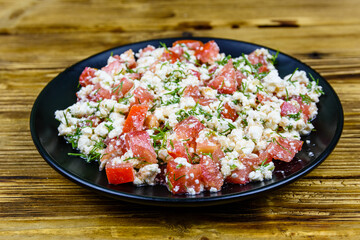 Salad with tomatoes, cottage cheese, dill and olive oil on a wooden table